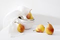 Still life with yellow-red pear Duchess in pile of bowls and a white embroidered napkin Royalty Free Stock Photo