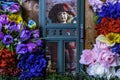 Young girl doll looking out screen door at spring flowers