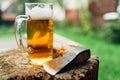 Still lifephoto of glass of fresh cold beer on wooden stub alongside axe. Rural concept, masculinity, coarse, rough wilderness