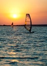 Still sea surface, man practicing wind surfing and golden sunset in sky Royalty Free Stock Photo