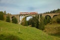 Old train passing on the old railway viaduct with modern center part over the valley in the mountains, Slovakia