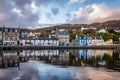 Still water of Tarbert Harbour reflect the beautifully painted houses on Barmore Rd in Argyll and Bute Scotland UK