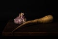 Stillife of garlic and a parsnip on a wooden table against a dark background