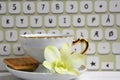 Stilllife of coffee cup with espresso, biscuit, flower and imitation of keyboard on a wooden background