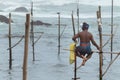 Stilt fisherman with his wooden rod facing back to the camera without a top, fishing in a traditional unique method Royalty Free Stock Photo