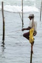 Stilt fisherman with his wooden rod facing side to the camera with his yellow pocket on the pole Royalty Free Stock Photo