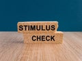 Stimulus CheckConcept. Words Stimulus Check on brick blocks. Beautiful wooden table, dark blue background. Copy space. Coronavirus