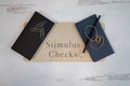 Stimulus checks painted on wood sign with check books framing