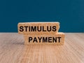 Stimulus package concept. Stimulus payment text on brick blocks. Beautiful wooden table, dark blue background. Royalty Free Stock Photo