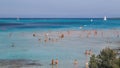 Stintino, Sardinia, Italy. Scenic view of La Pelosa beach with tourists standing in the water. Royalty Free Stock Photo