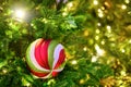 Stiped twisted balls on the Christmas tree and bokeh background of garland lights, copy space Royalty Free Stock Photo