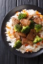 Stir-fried beef broccoli with rice and persimmon side dish close-up on a plate. Vertical top view Royalty Free Stock Photo