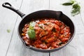 Stir-fried chicken breast in a sauce of tomatoes, garlic, basil and olive oil. Black cast-iron pan, light wooden table Royalty Free Stock Photo