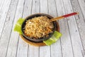 Stir-fried curly Chinese noodles with fried vegetables and chicken hole metal bowl and with chopsticks Royalty Free Stock Photo