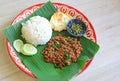 Stir-fried minced pork with basil leaves served with rice and fried egg on banana leaf on zinc tray over wooden table background Royalty Free Stock Photo