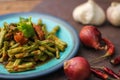 Stir fried pork belly and red curry paste with sting bean served in a blue plate on a wooden table Royalty Free Stock Photo