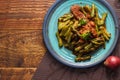 Stir fried pork belly and red curry paste with sting bean served in a blue plate on a wooden table Royalty Free Stock Photo