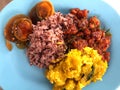 Stir-fried pumpkin eggs, fried preserved egg and stir-fried chicken with red curry paste served with riceberry