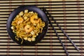 Stir fried rice noodles Pad Thai with prawns and tofu in plate on bamboo mat. Top view. Thai food Royalty Free Stock Photo