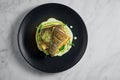 Stir-fried sea bass fillet with quinoa and broccoli garnish with creamy sauce, served in a black plate on a marble background. Royalty Free Stock Photo