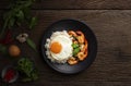 Stir-fried shrimp with basil Thai street food arranged on a black plate with a fried egg Spicy Thai food placed on a wooden table