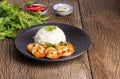 Stir-fried shrimp with basil Thai street food, arranged on a black plate Spicy Thai food placed on a wooden table. Top view with