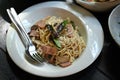 Stir fried spaghetti with crispy bacon, dried chili and basil leaf in white plate. Fusion food, Thai style food Royalty Free Stock Photo