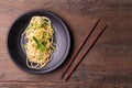 Stir-fried spaghetti or stir-fried noodles Tomato sauce and prawns on a black plate On a wooden table background. Top view Royalty Free Stock Photo