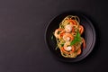 Stir-fried spaghetti or stir-fried noodles Tomato sauce and prawns on a black plate On a wooden table background. Top view Royalty Free Stock Photo