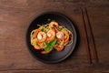 Stir-fried spaghetti or stir-fried noodles Tomato sauce and prawns on a black plate On a wooden table background. Top view Royalty Free Stock Photo