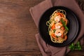 Stir-fried spaghetti or stir-fried noodles Tomato sauce and prawns on a black plate On a wooden table background. Top view Royalty Free Stock Photo