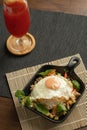 Stir-fried Thai basil with minced pork meat, carrots, and baby corns, with fried egg and fresh Thai basils sort in a black small Royalty Free Stock Photo