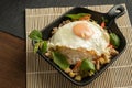 Stir-fried Thai basil with minced pork meat, carrots, and baby corns, with fried egg and fresh Thai basils sort in a black small Royalty Free Stock Photo