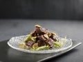 Stir-fried US Angus Beef Cube with Foie Gras Pate served in a dish side view on grey background