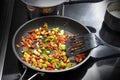 Stir fried vegetables like bell pepper, onion and leek with spices in a black frying pan on the stovetop with other pots, cooking Royalty Free Stock Photo