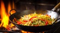 Stir-fried vegetables and noodles cooking in wok over open flame in rustic kitchen setting, close-up Royalty Free Stock Photo