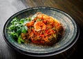 Stir fry noodles with vegetables and shrimps in plate on wooden table Royalty Free Stock Photo