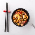 Stir fry noodles or wok noodles frying with prawns and mussels in black bowl and chopsticks side view Royalty Free Stock Photo