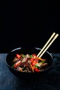 Stir fry soba noodles with beef and vegetables in wok on dark background, Asian noodles with beef WOK in black bowl Royalty Free Stock Photo