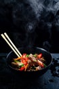Stir fry soba noodles with beef and vegetables in wok on dark background, Asian noodles with beef WOK in black bowl Royalty Free Stock Photo
