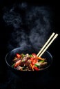 Stir fry soba noodles with beef and vegetables in wok on dark background, Asian noodles with beef WOK in black bowl Royalty Free Stock Photo