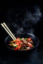 Stir fry soba noodles with beef and vegetables in wok on dark background, Asian noodles with beef WOK in black bowl Royalty Free Stock Photo