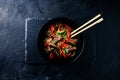 Stir fry soba noodles with beef and vegetables in wok on dark background, Asian noodles with beef WOK in black bowl Royalty Free Stock Photo