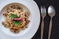 Stir fry Spaghetti with salted fish, Thai spices and dry chili, in white dish, with fork and spoon