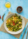 Stir fry, thin rice noodles with squid and okra in a gray plate on a light blue concrete background. Okra recipes