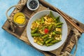 Stir fry, thin rice noodles with squid and okra in a gray plate on a light blue concrete background. Okra recipes