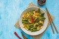 Stir fry, thin rice noodles with squid and okra in a gray plate on a light blue concrete background. Okra recipes
