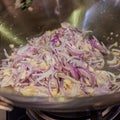 Stir-frying chopped onions, shallots and garlic in a wok.