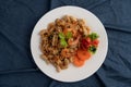Stir shrimp macaroni on a white plate with carrots, tomatoes and salad