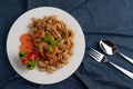 Stir shrimp macaroni on a white plate with fork, spoon, carrots, tomatoes and salad